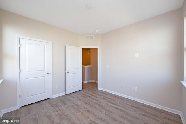 unfurnished bedroom with baseboards, visible vents, and wood finished floors