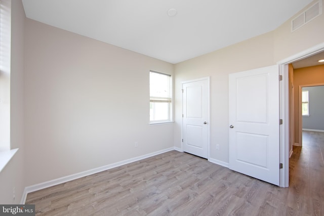 unfurnished bedroom with baseboards, wood finished floors, and visible vents