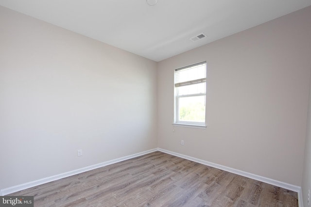 spare room with baseboards, light wood finished floors, and visible vents
