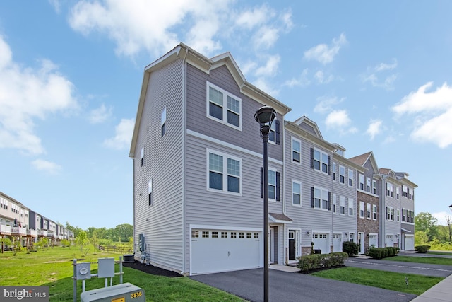 townhome / multi-family property with a garage, aphalt driveway, central air condition unit, and a front yard