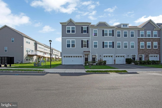 townhome / multi-family property with aphalt driveway, a residential view, and a garage