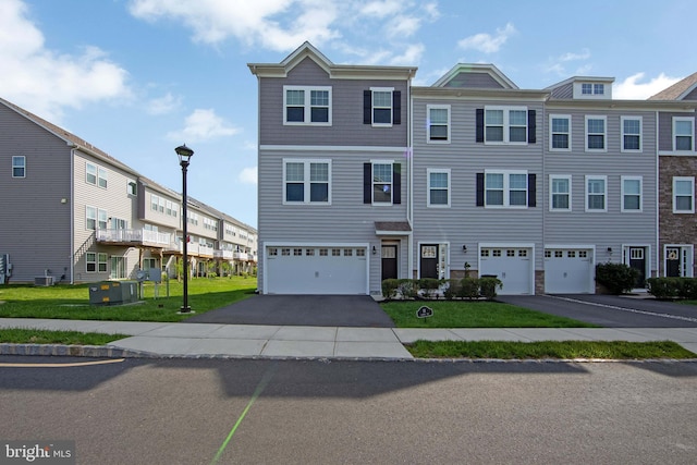 view of property with an attached garage, driveway, and a front yard
