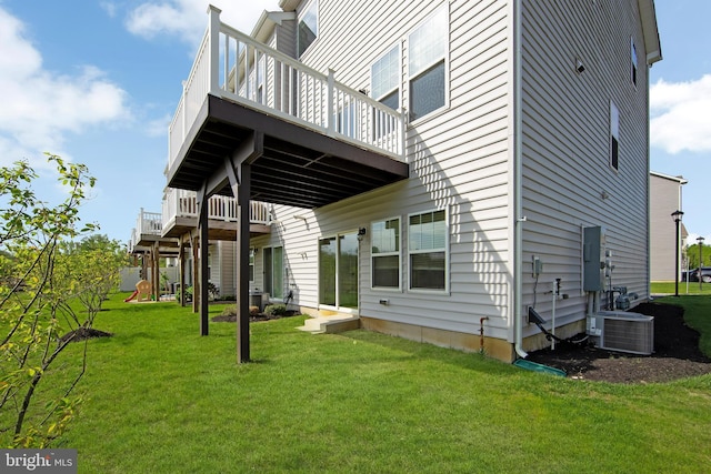 rear view of house featuring a lawn, a deck, and cooling unit