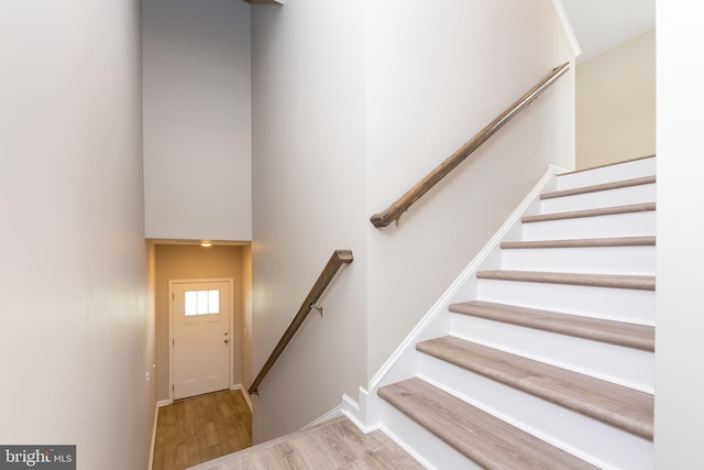 stairs featuring baseboards, a high ceiling, and wood finished floors