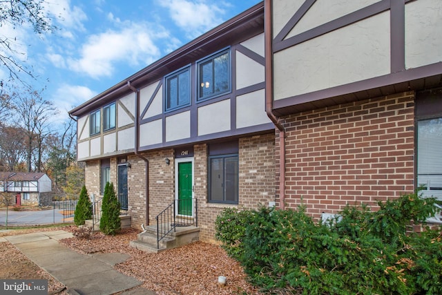 exterior space featuring brick siding and stucco siding