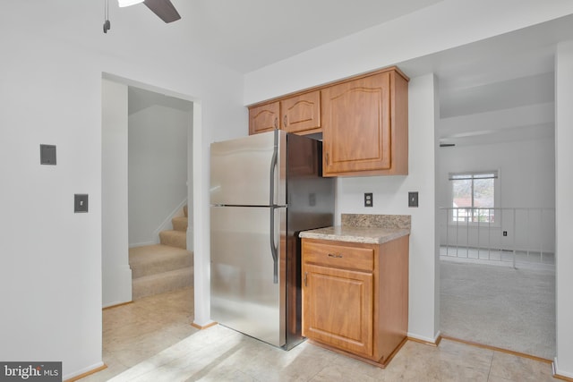 kitchen featuring light countertops, freestanding refrigerator, a ceiling fan, and light colored carpet