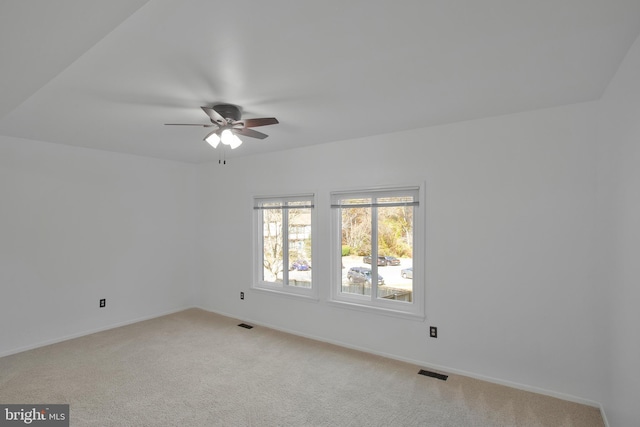 unfurnished room with baseboards, light carpet, a ceiling fan, and visible vents