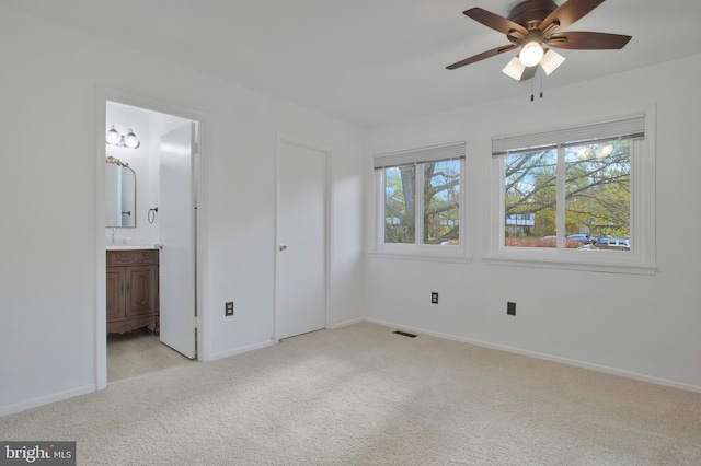 unfurnished bedroom with baseboards, connected bathroom, visible vents, and light carpet