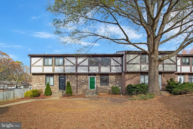 townhome / multi-family property featuring fence, stucco siding, entry steps, and brick siding