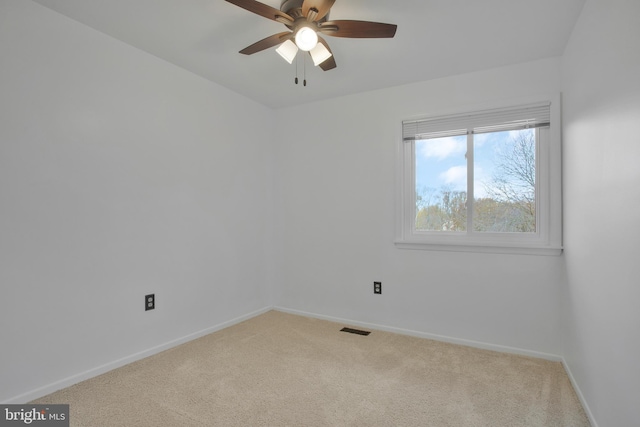 carpeted spare room featuring baseboards, a ceiling fan, and visible vents