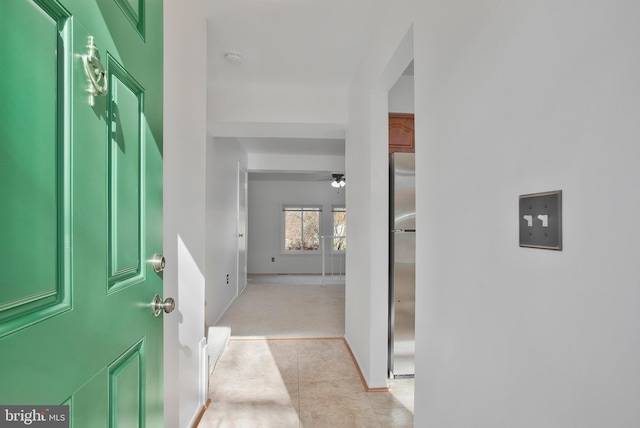 hall with light tile patterned floors, baseboards, and light colored carpet