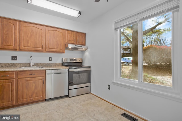 kitchen with a sink, appliances with stainless steel finishes, under cabinet range hood, and a wealth of natural light