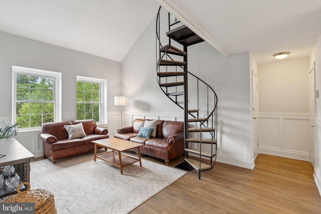 living area featuring light wood-style floors, stairs, wainscoting, and a decorative wall