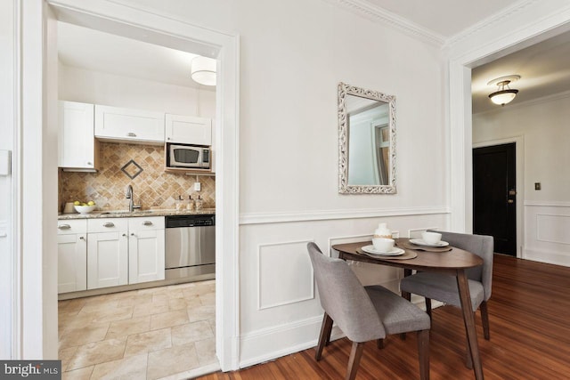 dining room with crown molding, wainscoting, and a decorative wall