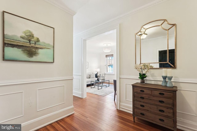 hall featuring crown molding, wainscoting, and wood finished floors