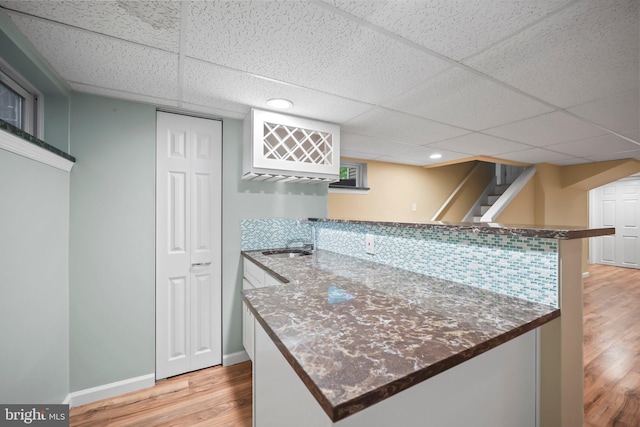2115 Pennington, Ewing, NJ 08638 - kitchen with a peninsula, light wood-style floors, a sink, a paneled ceiling, and dark stone countertops