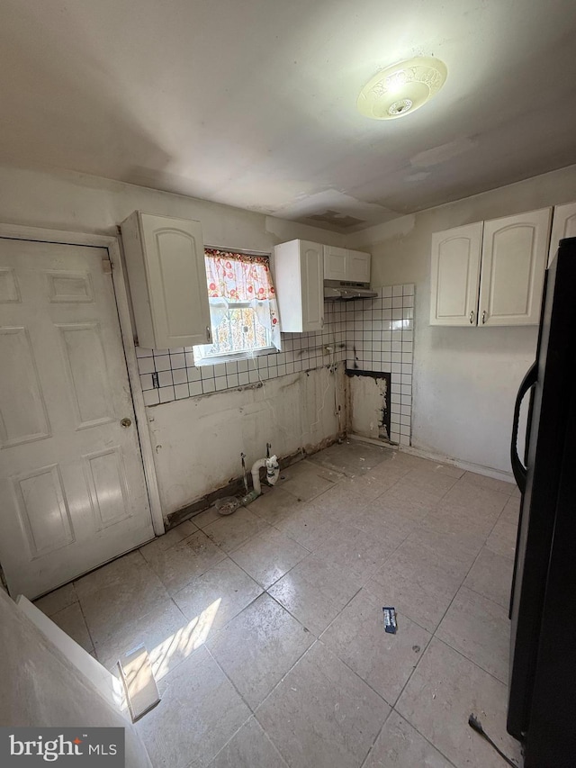 kitchen featuring freestanding refrigerator and white cabinetry