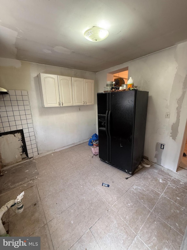 interior space with white cabinets, black refrigerator with ice dispenser, and a tile fireplace