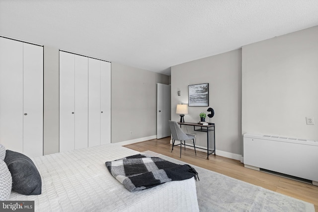 1301 S Arlington Ridge Rd Unit 208, Arlington, VA 22202 - bedroom with wood finished floors, radiator heating unit, multiple closets, a desk, and baseboards