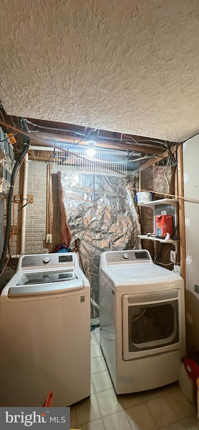 laundry area with a textured ceiling, washing machine and dryer, and laundry area