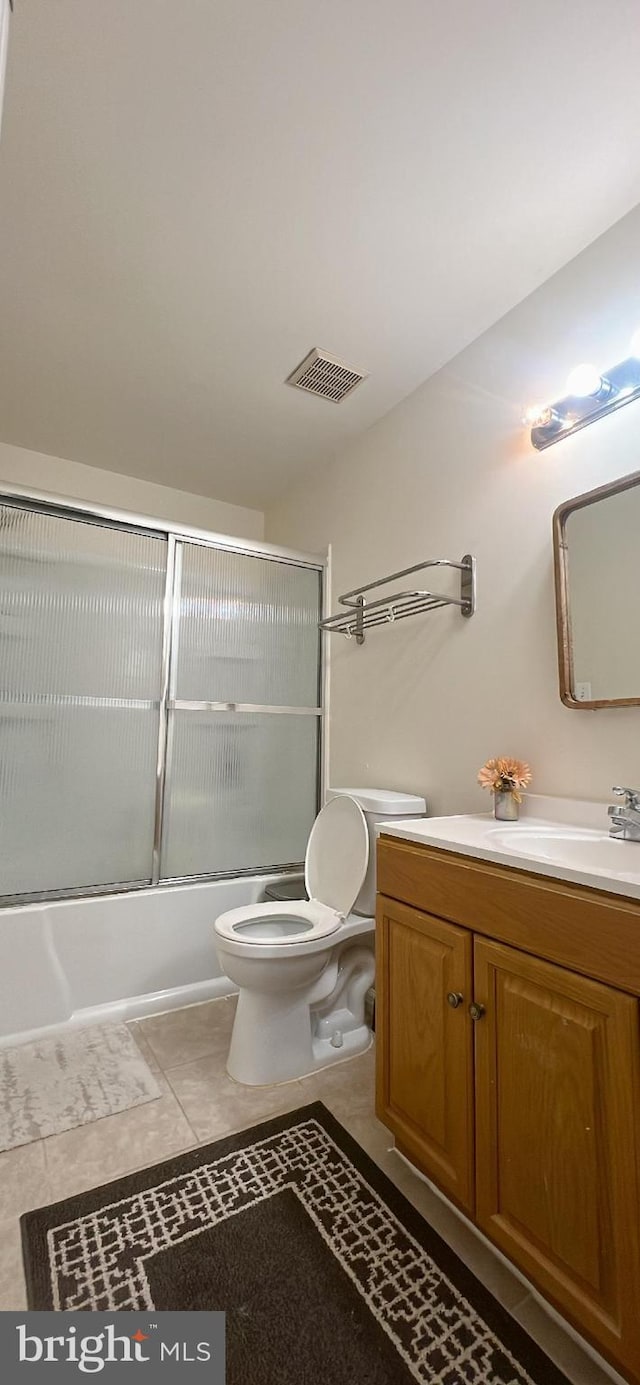 bathroom with visible vents, vanity, toilet, bath / shower combo with glass door, and tile patterned floors