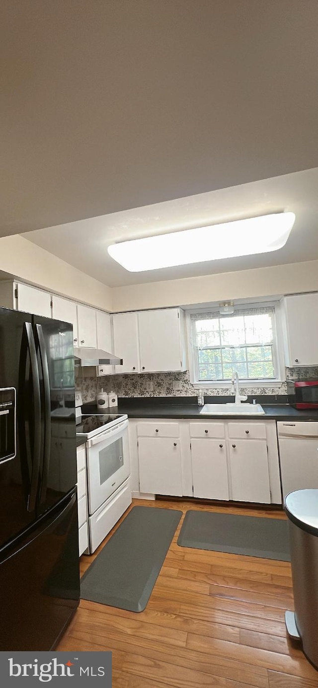 kitchen featuring backsplash, a sink, light wood finished floors, white appliances, and white cabinetry