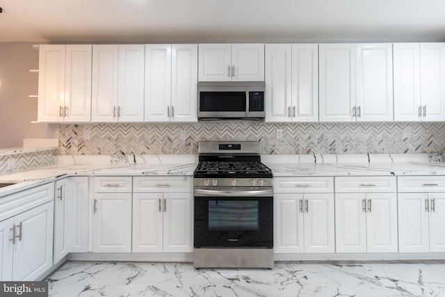 kitchen with light stone counters, marble finish floor, white cabinets, and stainless steel appliances