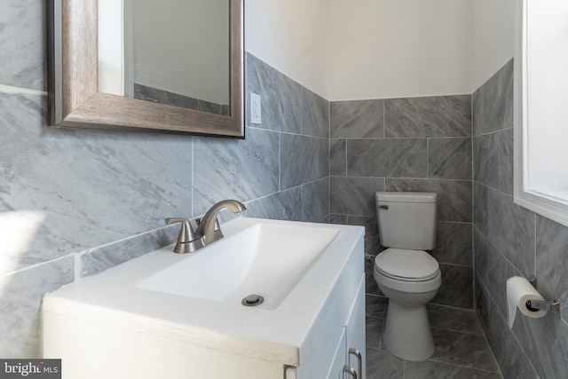 bathroom featuring vanity, toilet, and tile walls