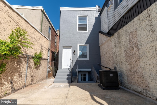 property entrance with fence, cooling unit, and brick siding