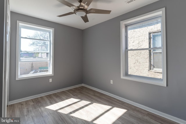 empty room with baseboards, wood finished floors, and a healthy amount of sunlight