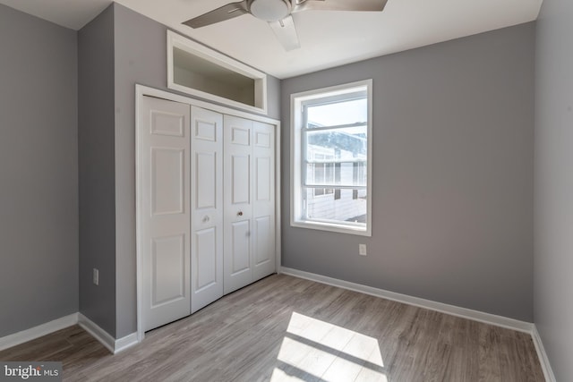 unfurnished bedroom featuring a closet, a ceiling fan, baseboards, and wood finished floors