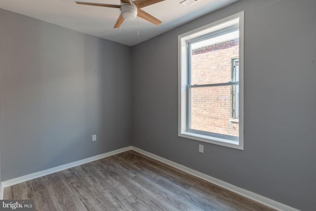 spare room featuring a ceiling fan, baseboards, and wood finished floors