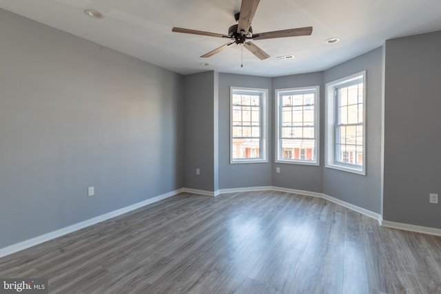 spare room featuring a ceiling fan, baseboards, visible vents, and wood finished floors