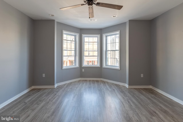 unfurnished room with visible vents, a ceiling fan, baseboards, and wood finished floors