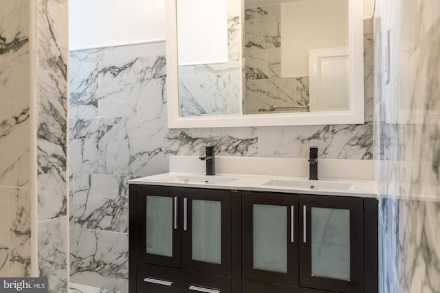 full bathroom with a sink, tile walls, and double vanity