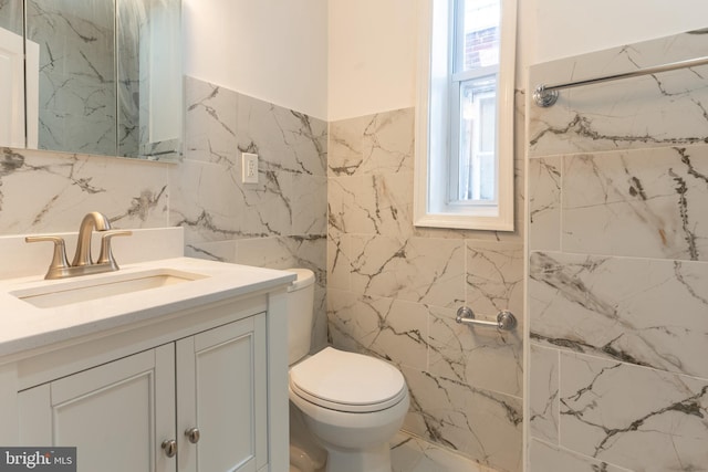 bathroom featuring toilet, tile walls, and vanity