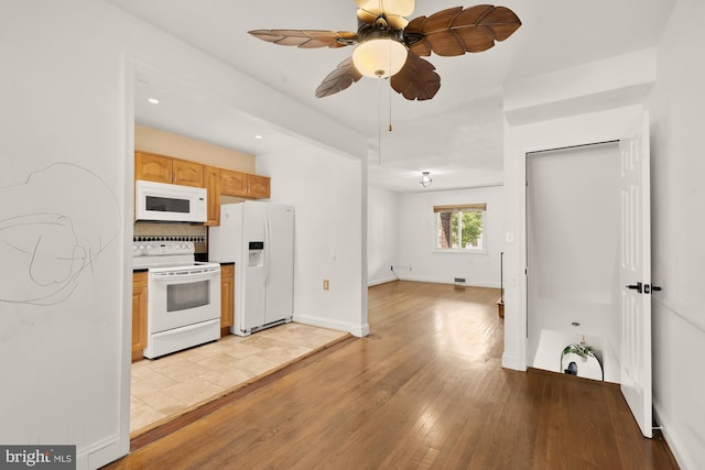 kitchen with tasteful backsplash, light wood-type flooring, baseboards, light brown cabinets, and white appliances