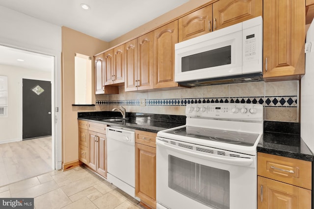 kitchen featuring tasteful backsplash, a sink, dark stone counters, recessed lighting, and white appliances