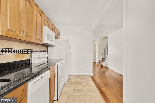 kitchen with backsplash, arched walkways, dark stone countertops, recessed lighting, and white appliances