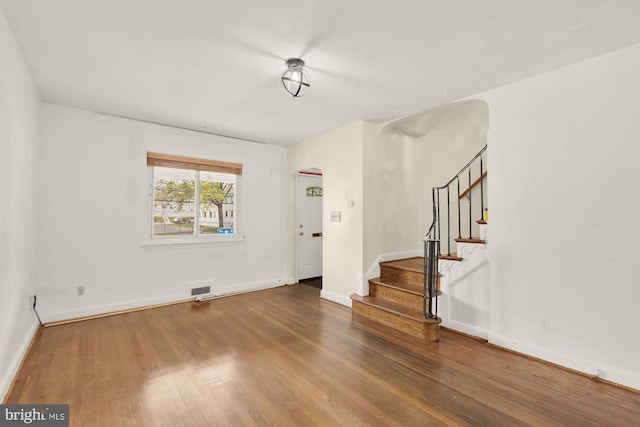 entryway featuring visible vents, arched walkways, wood finished floors, baseboards, and stairs