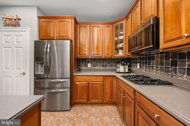 13073 Taverner Loop, Woodbridge, VA 22192 - kitchen with decorative backsplash, brown cabinetry, and stainless steel appliances
