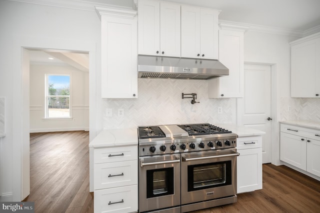 kitchen with dark wood-type flooring, ornamental molding, under cabinet range hood, and double oven range