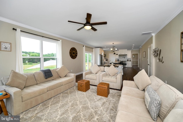living room featuring ornamental molding, ceiling fan with notable chandelier, wood finished floors, and visible vents