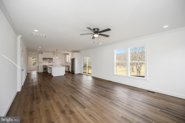 unfurnished living room featuring plenty of natural light, baseboards, ornamental molding, and a ceiling fan