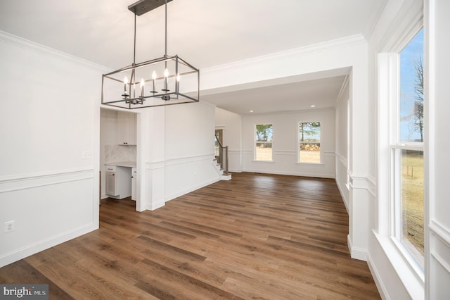 unfurnished dining area with ornamental molding, dark wood-style flooring, stairs, and a notable chandelier