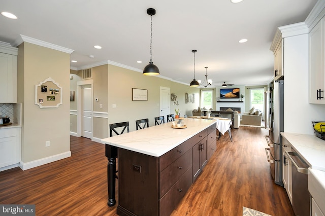 kitchen featuring dark wood-style flooring, appliances with stainless steel finishes, recessed lighting, open floor plan, and a kitchen bar