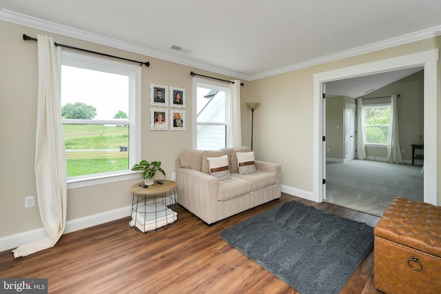 living area featuring visible vents, baseboards, crown molding, and wood finished floors