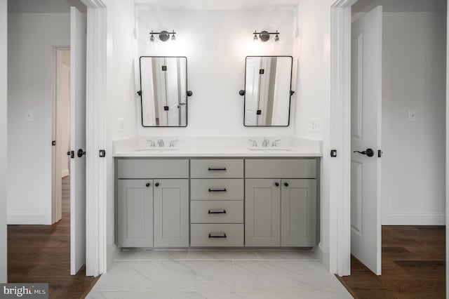 full bath featuring double vanity, baseboards, and a sink