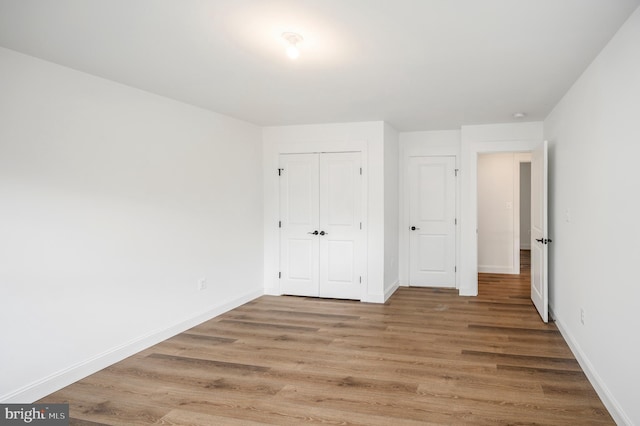 unfurnished bedroom with a closet, baseboards, and light wood-style floors