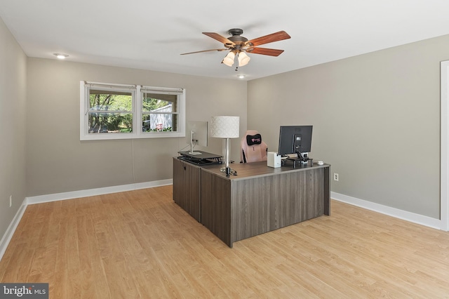 office space featuring baseboards, ceiling fan, and light wood finished floors